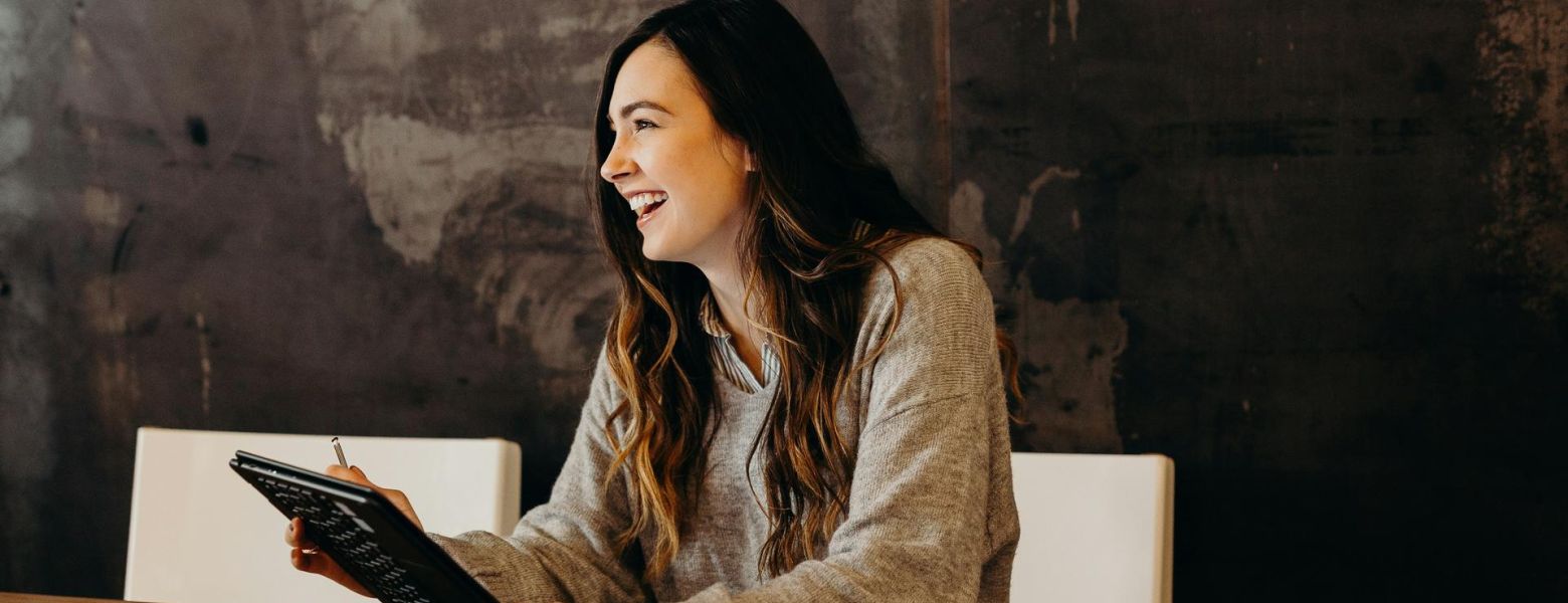 women smiling at a table with a device