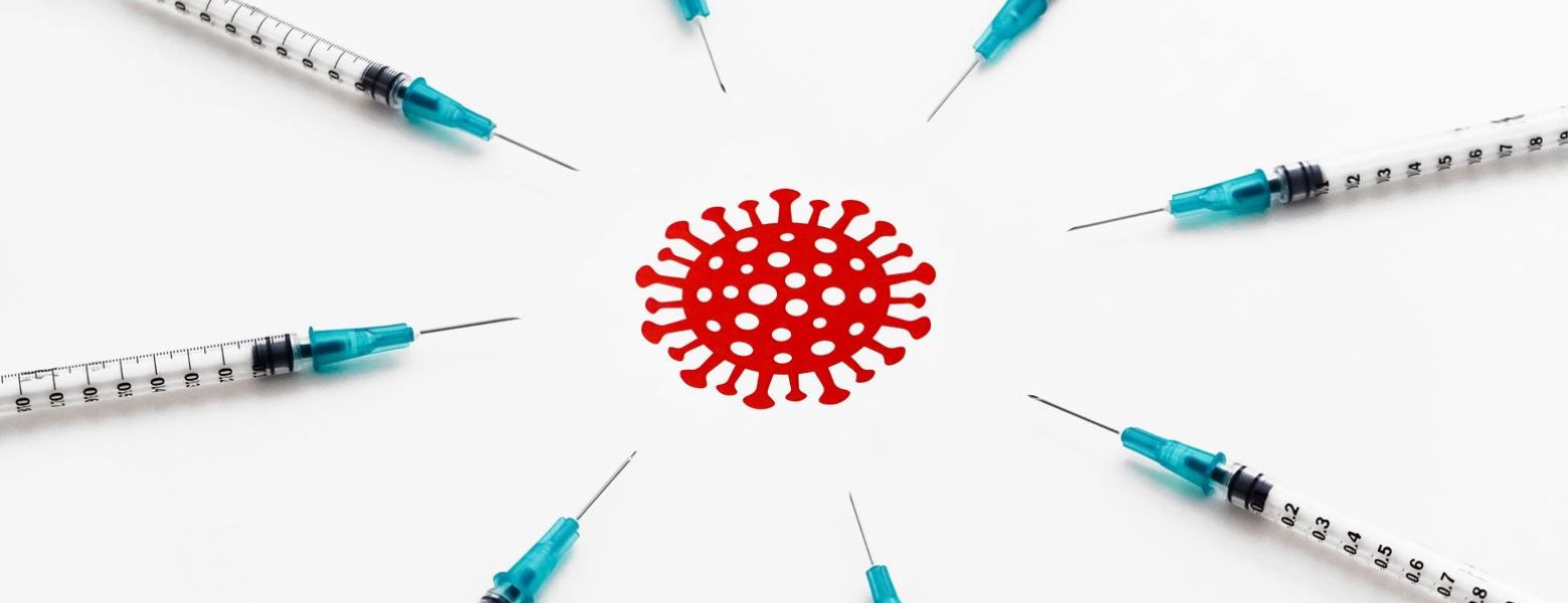 vaccine needles all pointing at red covid virus in the middle