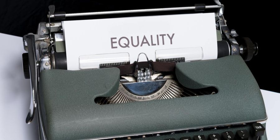 old typewriter with a page that says equality, indoors