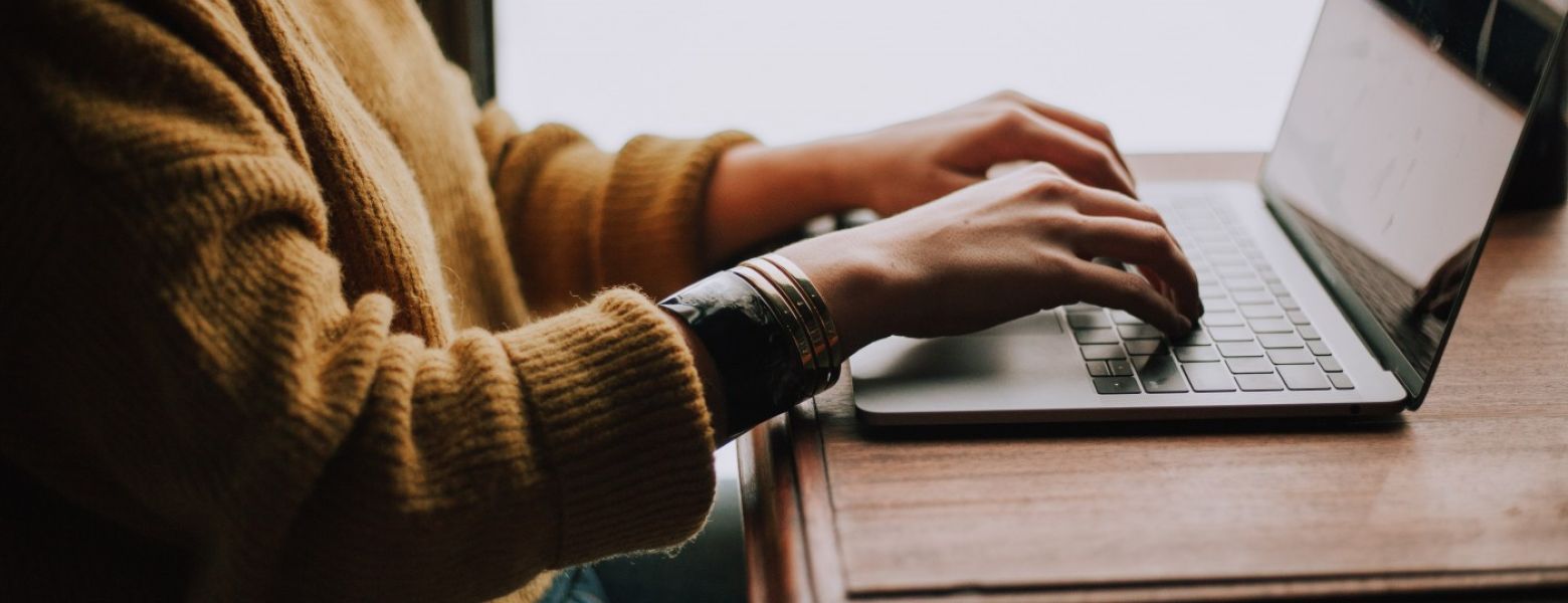 Person typing on a laptop computer at a desk indoors