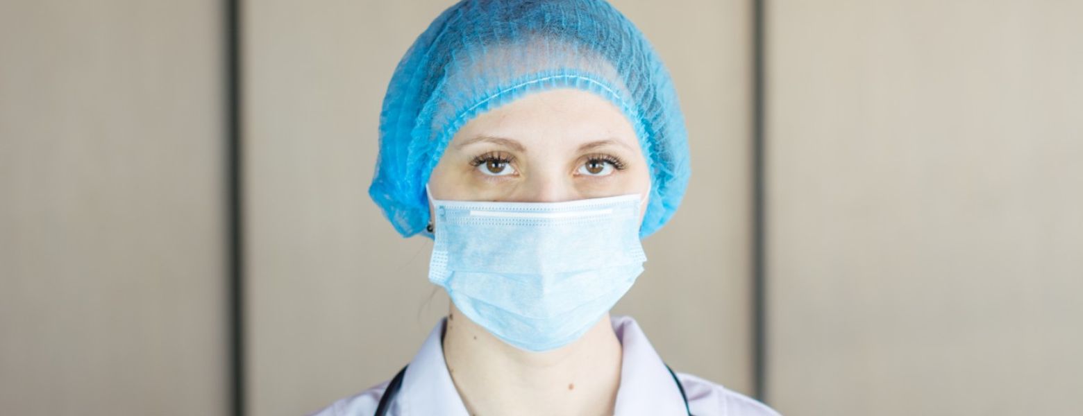 nurse looking at the camera indoors with a hairnet and mask